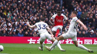 Arsenal withstand late Tottenham siege to stay in race